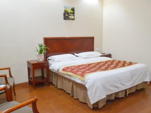 a bedroom with a large bed with a wooden headboard at GreenTree Inn ShanDong LaiWu West LaiWu Road Express Hotel in Laiwu