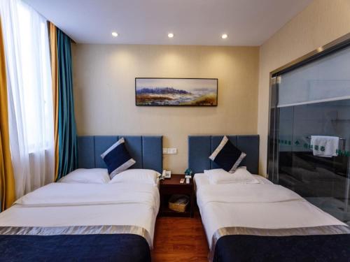 two beds in a hotel room with at Greentree Inn Jiangsu Suzhou Wujiang yongkang Pedestrian Road Express Hotel in Suzhou
