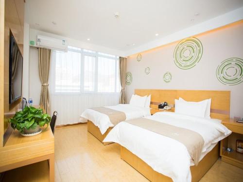 een hotelkamer met 2 bedden en een televisie bij GreenTree Inn Tangshan Qianxi Bus Terminal Express Hotel in Qian'an