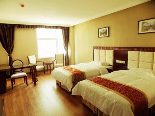 a hotel room with two beds and a desk at GreenTree Inn Hebei Chengde Luanping Luanyang Road Xiangyuan Road Express Hotel in Beiliying