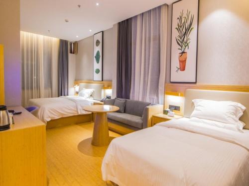 een hotelkamer met 2 bedden en een bank bij GreenTree Inn Fuzhou South Railway Station Business Hotel in Fuzhou