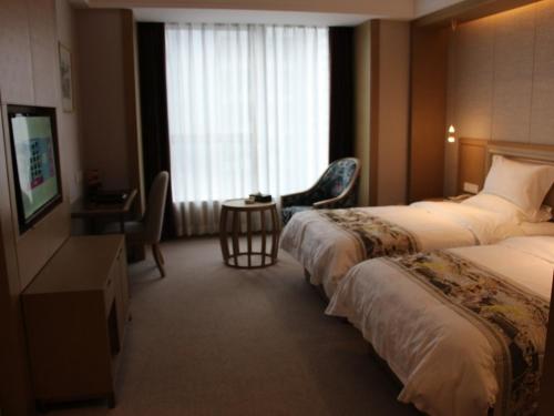 a hotel room with two beds and a desk and a television at GreenTree Eastern Shaoxing Keqiao Jindizizaicheng Hotel in Shaoxing