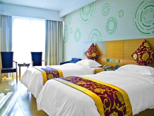 a hotel room with three beds and a desk at GreenTree Inn Jiangsu Wuxi Beitang District Xinsheng Express Hotel in Wuxi