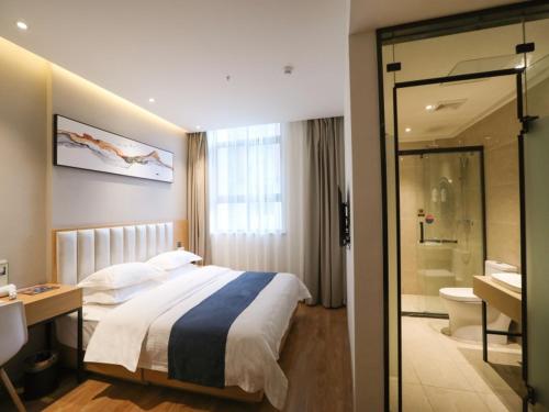 a hotel room with a bed and a bathroom at Shell Xinzheng Airport Port Huaxia Avenue Hotel in Xinzheng