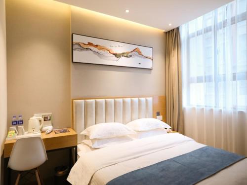 um quarto com uma cama, uma secretária e uma janela em Shell Xinzheng Airport Port Huaxia Avenue Hotel em Xinzheng