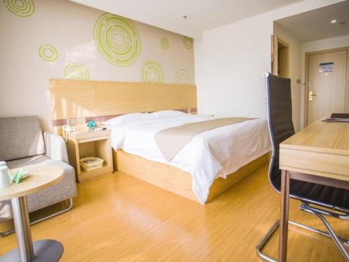 een slaapkamer met een bed, een bureau en een stoel bij GreenTree Inn Heze Shanxian Huxi South Road Express Hotel in Shan