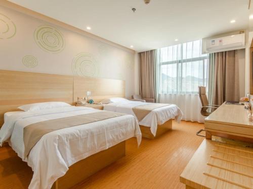 a hotel room with two beds and a window at GreenTree Inn LiuAn Huoshan County Yingjia Avenue County Hospital Express Hotel in Huoshan