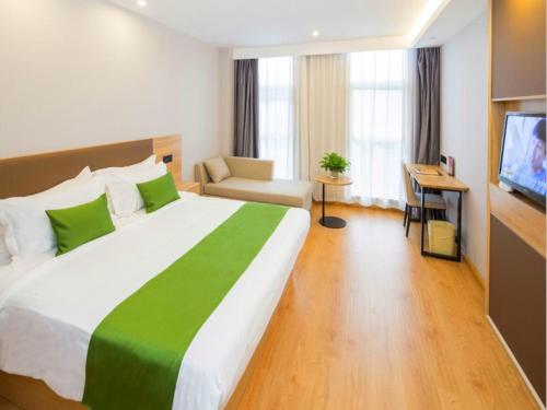 um quarto de hotel com uma cama grande e uma televisão em GreenTree Inn Tianjin Xiqing Development Zone Renrenle Square Express Hotel em Tianjin
