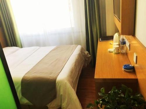 a hotel room with a bed and a wooden desk at Vatica Hefei Yaohai District Linquan Road Anhui Big Market Hotel in Hefei