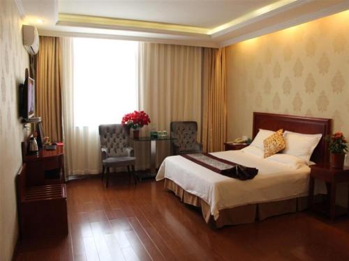une chambre d'hôtel avec un lit, une table et des chaises dans l'établissement GreenTree Inn Shandong Jining Zoucheng East Kuangjian Road Business Hotel, à Zoucheng