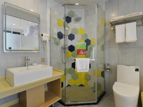 een badkamer met een wastafel en een douche met een toilet bij Vatica Huanggang Luotian County City Square Hotel in Luotian