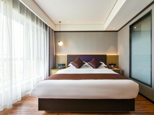 a bedroom with a large bed and a large window at GYA Langfang Art Avenue International Airport Hotel in Langfang