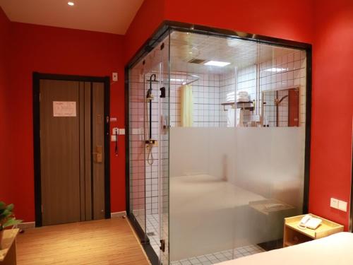 La salle de bains est pourvue d'une douche en verre et d'un mur rouge. dans l'établissement Shell Xingtai City Qiaodong DistrictXinhua South Road Hotel, à Xingtai
