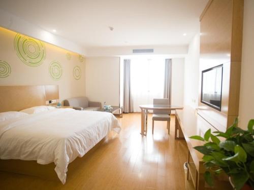 a bedroom with a white bed and a table at GreenTree Inn Fuyang Linquan County Yiwu Trade City Express Hotel in Jinzhuang