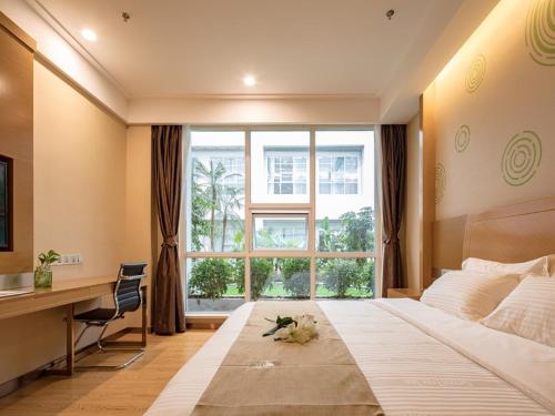 a bedroom with a large bed with a desk and a window at GreenTree Inn Wuxi Jiangyin City Renmin East Road Liangchen Square Business Hotel in Jiangyin