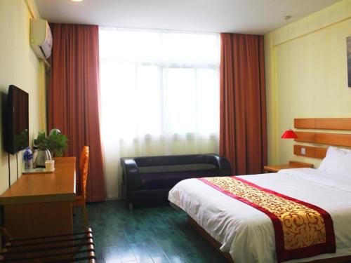 Pokój hotelowy z łóżkiem, biurkiem i oknem w obiekcie Shell Xinyu City Railway Station Plaza Hotel w mieście Xinyu