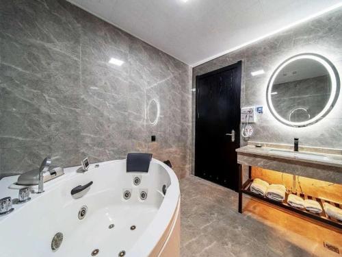 ein Badezimmer mit einer großen weißen Badewanne und einem Spiegel in der Unterkunft GreenTree Alliance JiangXi ShangRao YiYang County ZhiMin Aveune YingBin Avenue Hotel in Yiyang