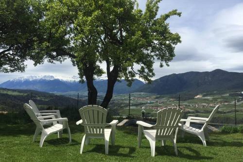 four white chairs and a table under a tree at Residence Bellavista in Fondo