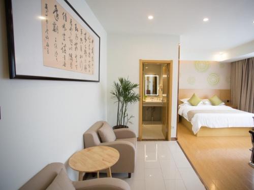 a hotel room with a bed and a couch and a table at GreenTree Inn Huai Nan Shou County Zijin Road Express Hotel in Majiaxu