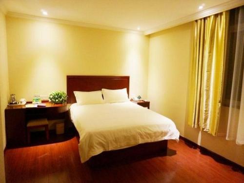 a bedroom with a white bed and a desk and a window at GreenTree Inn Shandong Zaozhuang Xuecheng District Road Taishan Road Road Communist Youth League School Express Hotel in Zaozhuang