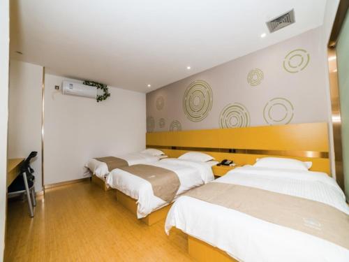 a room with three beds and a desk in it at GreenTree Inn Suzhou Zhangjiagang City Jingang Town Express Hotel in Zhangjiagang