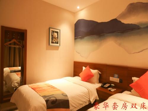 a bedroom with two beds and a painting on the wall at Shell Liaocheng Linqing City Bus Station Hotel in Liaocheng