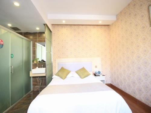 a bedroom with a large white bed with two pillows at GreenTree Inn WenZhou LuCheng XiaoNanMen Express Hotel in Wenzhou