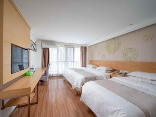 a hotel room with two beds and a flat screen tv at GreenTree Inn Yancheng National Fitness Center Express Hotel in Yancheng