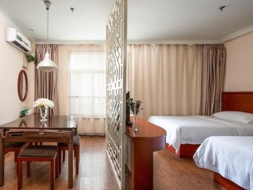 a hotel room with two beds and a desk and a table at GreenTree Inn Jiangsu Yancheng Economic Development Zone Management Committee Express Hotel in Yancheng