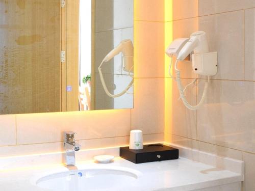 La salle de bains est pourvue d'un lavabo, d'un miroir et d'un téléphone. dans l'établissement GreenTree Inn Suzhou Yongqiao District Nanxiang Hengtai City Business Hotel, à Suzhou