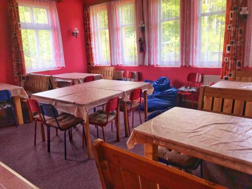 uma sala de jantar com mesas, cadeiras e janelas em chata Švýcarský dvůr em Janske Lazne