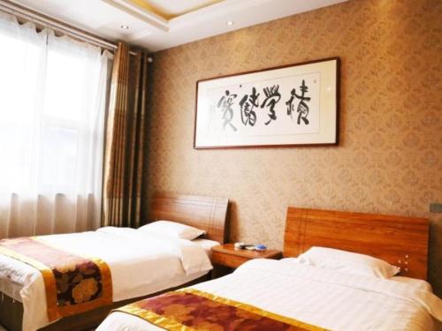 una camera d'albergo con due letti e una foto a parete di Shell Jinzhong Pingyao Ancient City East Gate Hotel a Pingyao