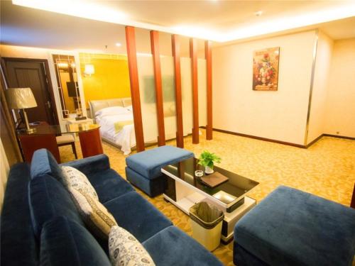 a living room with a blue couch and a bed at GreenTree Alliance Nanping Yanping District Xinjian Road Hotel in Nanping