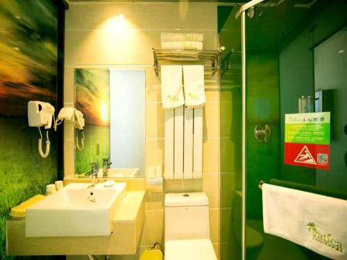 a bathroom with a sink and a toilet and a mirror at GreenTree Hospitality Group Ltd Vatica Jiuquan West Han Shengsheng Shengshi Hotel in Jiuquan