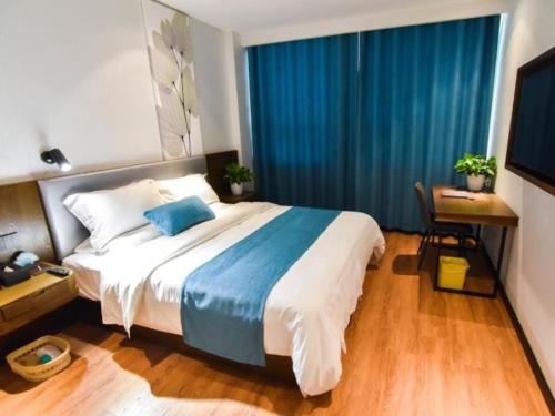 a bedroom with a large bed with blue curtains at GreenTree Rizhao Lanshan Coach Station Hotel in Rizhao