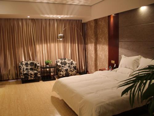 ein Schlafzimmer mit einem großen Bett und zwei Stühlen in der Unterkunft GreenTree Inn Jiangsu Nantong Tongzhou Shiji Avenue Jianghaihuangdu Express Hotel in Tongzhou