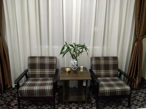 dwa krzesła i stół z wazonem w obiekcie GreenTree Alliance Xinyang Pingqiao District Nanjing Road Dongyang Hotel w mieście Xinyang