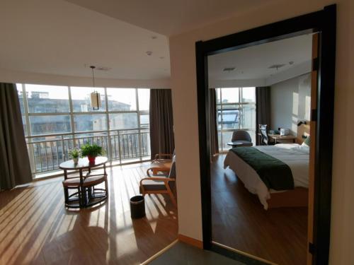 - une chambre avec un lit, une table et un balcon dans l'établissement GreenTree Inn Anqing City Huai Ning County Wanhe Road Select Hotel, à Qianshan