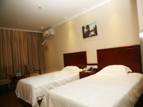 two beds in a hotel room with white sheets at GreenTree Inn Xinjiang Tulufan North Xihuan Road Express Hotel in Turfan