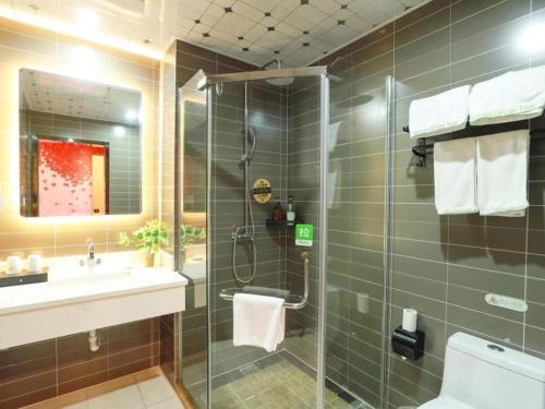 a bathroom with a glass shower and a sink at GreenTree Inn Wuxi Yixing High-speed Railway Station Dingshu Town Tongshu Road Express Hotel in Wuxi