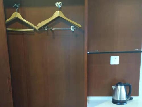 a wooden door with a tea kettle on a counter at GreenTree ShangHai JinShan Wanda Plaza Longxiang Road Express Hotel in Jinshan