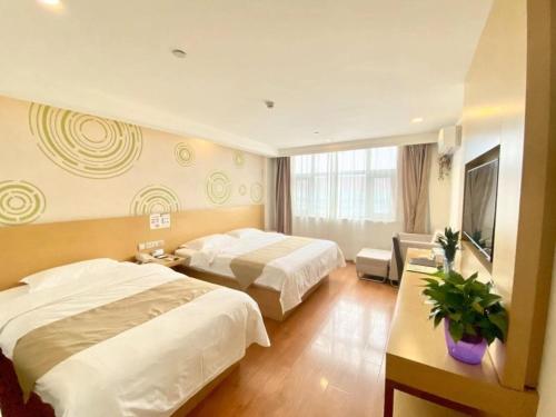 a hotel room with two beds and a television at GreenTree Inn Tianjin Xiqing District Xiuchuan Road Sunshine 100 in Tianjin