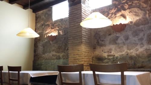 a dining room with tables and chairs and two lights at Casa Rural con encanto "Los Postigos" in Baños de Montemayor