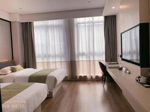 a hotel room with two beds and a flat screen tv at Gya Jiaxing Pinghu City Wuyue Square Shengli Road Hotel in Jiaxing