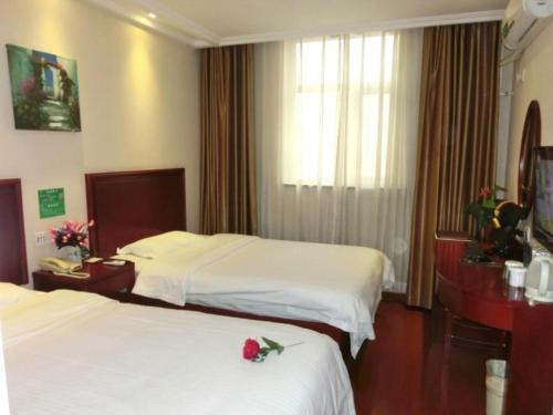 a hotel room with two beds with roses on them at GreenTree Inn Beijing Fangshan Liangxiang Suzhuang Express Hotel in Fangshan