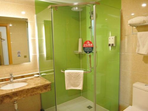 a green bathroom with a shower and a sink at GreenTree Alliance Liaocheng Dongchangfu District Chenkou Road Liaocheng University Hotel in Liaocheng