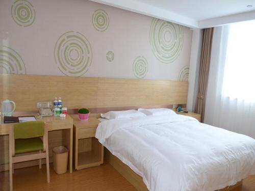 a bedroom with a bed and a desk with a white bedspread at GreenTree Inn Tangshan Lubei District Hancheng Likang Hospital Express Hotel in Tangshan