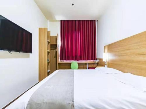 a bedroom with a large bed and a red curtain at GreenTree Inn Tianjin Dagang Shihua Road Hotel in Binhai