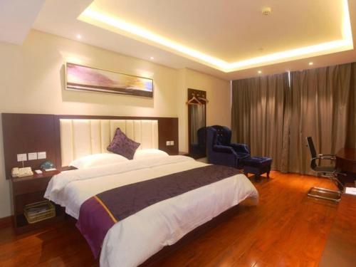 YixingにあるGreenTree Inn Jiangsu Wuxi Yixing Post Building Express Hotelの大きなベッドと椅子が備わるホテルルームです。