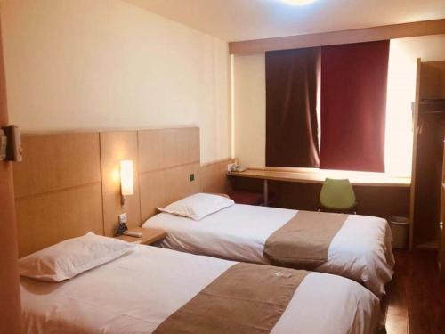 a hotel room with two beds and a window at GreenTree Inn Tianjin Dagang Shihua Road Hotel in Binhai